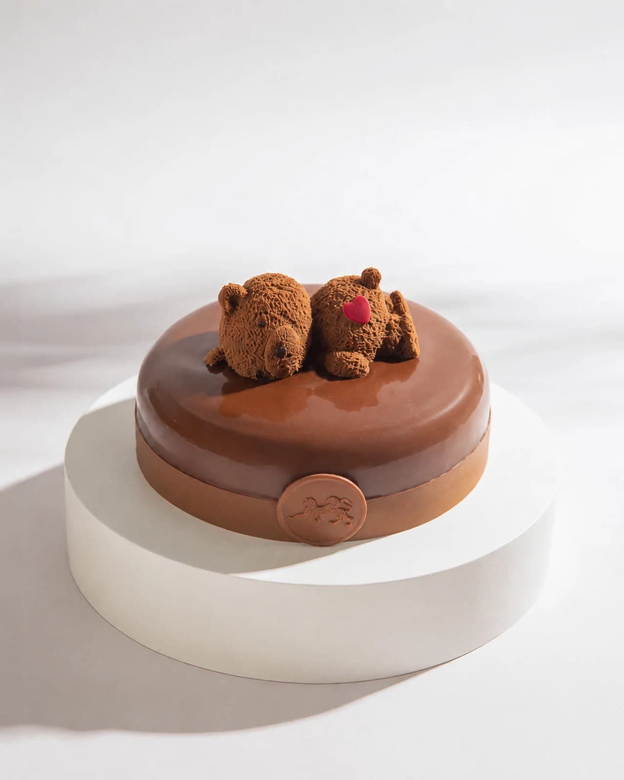 A glazed chocolate cake topped with two chocolate bears